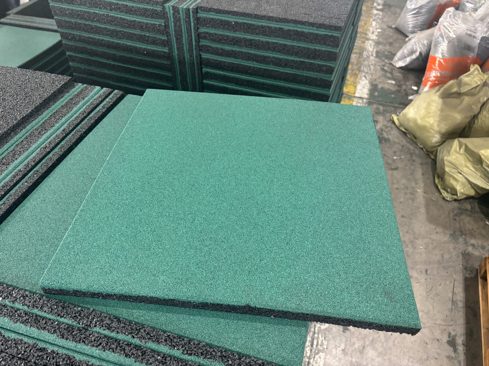 Green rubber gym floor tiles stacked for production