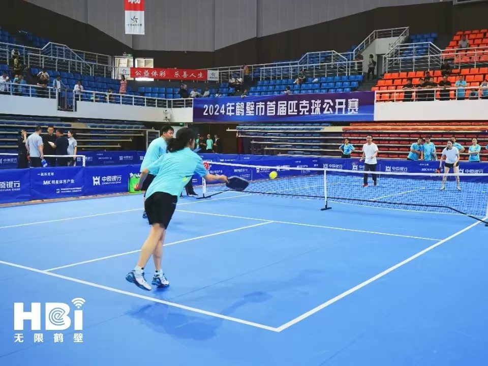 Players competing on a blue indoor pickleball court