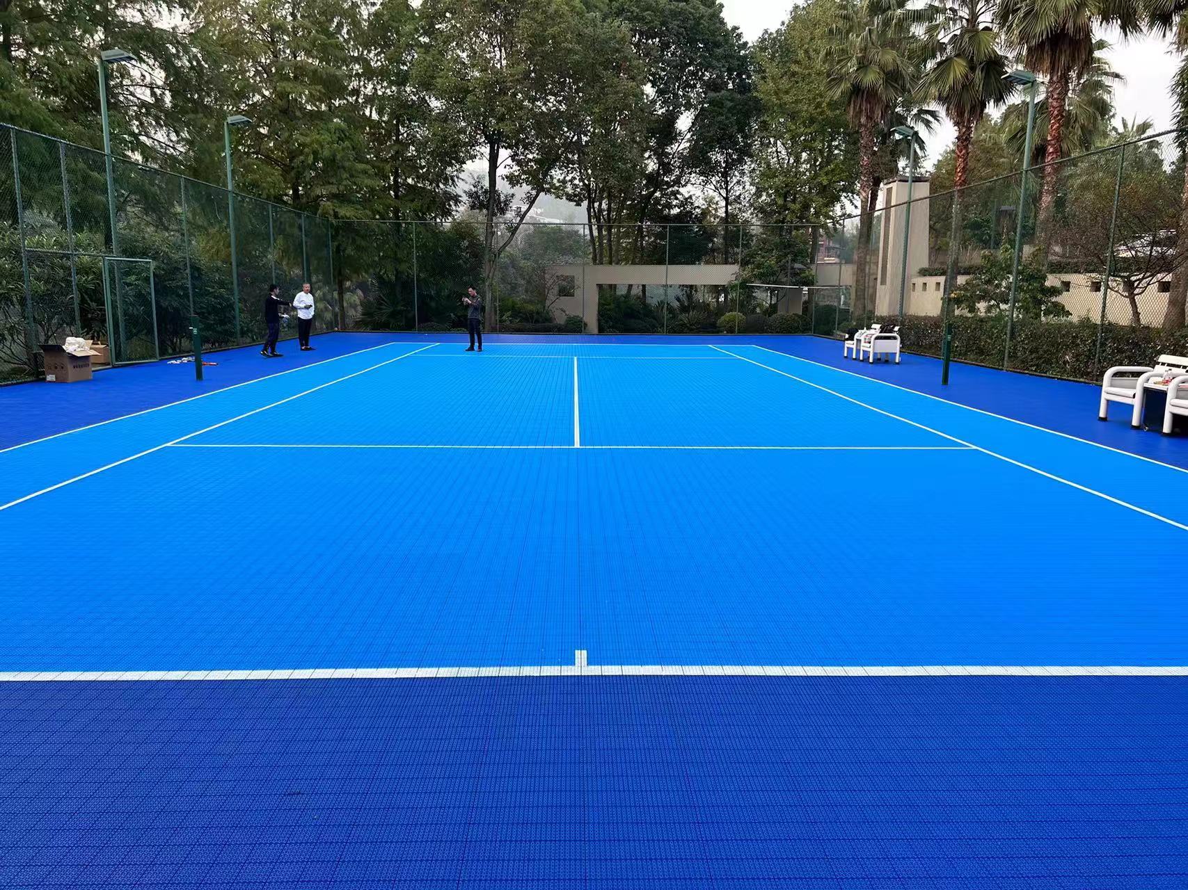 Blue Enlio outdoor tennis court surrounded by mature landscaping