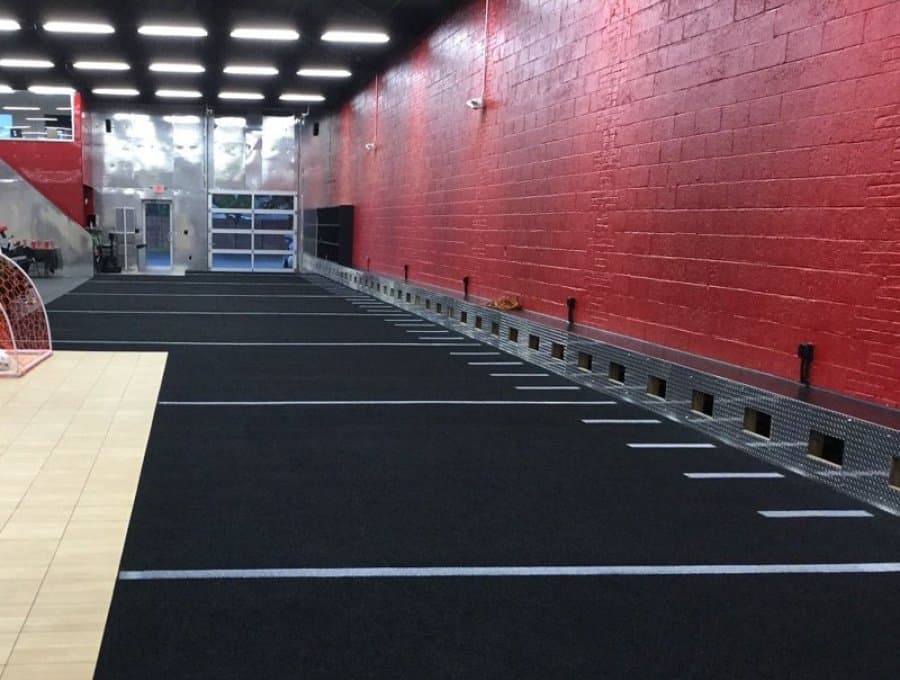 Long black functional training lanes installed beside a red gym wall