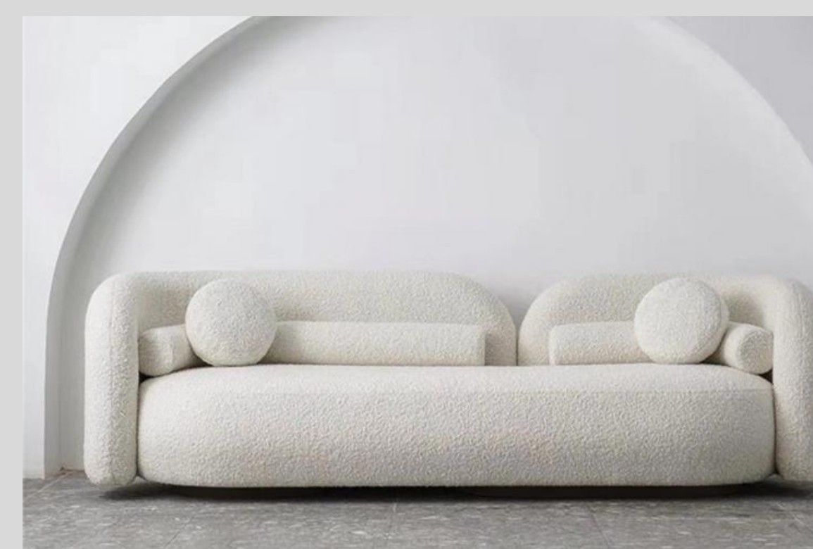 Cream textured sofa with rounded arms and circular and cylindrical bolster cushions