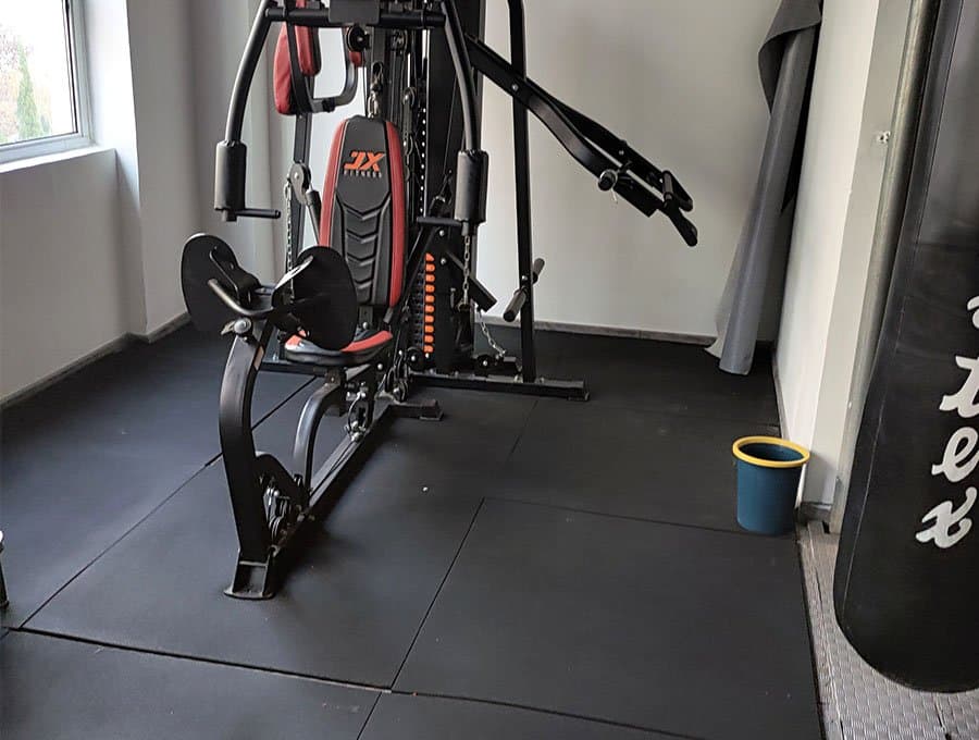 Home gym using black rubber floor tiles beneath strength equipment