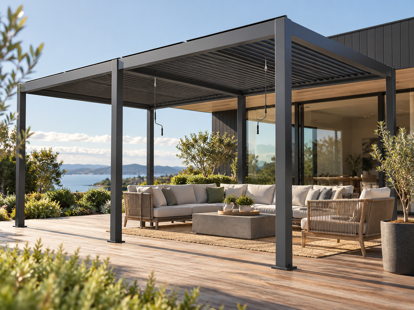 Lifestyle visualisation of an open-sided charcoal CADARN double-bay louvre pergola over a coastal outdoor lounge