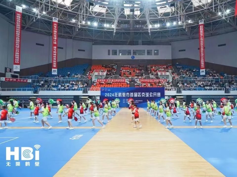 Large group event on blue indoor pickleball courts inside an arena
