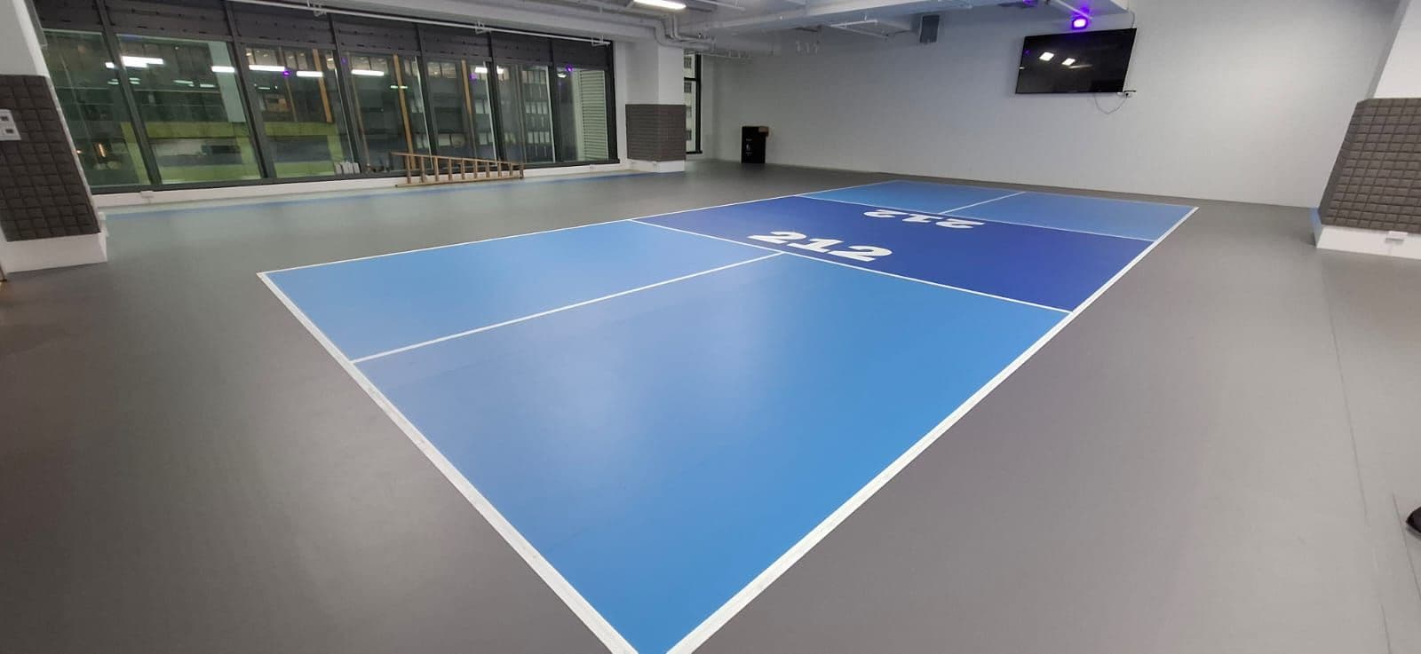Blue roll-out pickleball court installed inside a large indoor hall