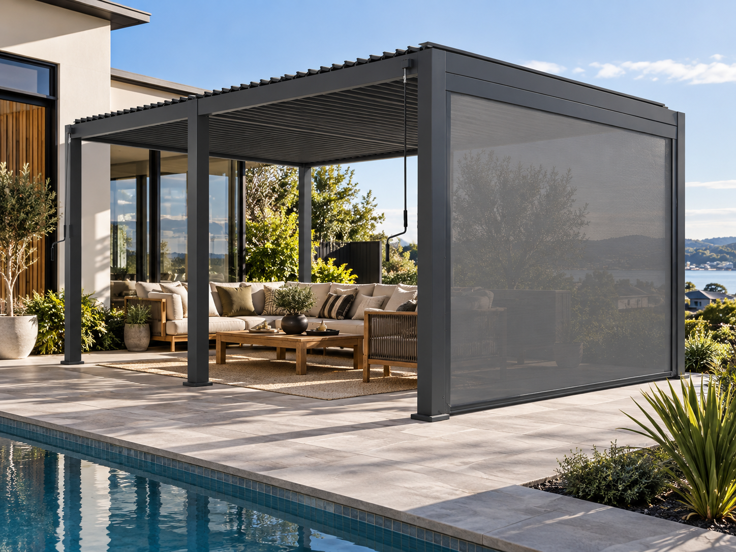 Lifestyle visualisation of a charcoal CADARN double-bay louvre pergola beside a pool with an integrated retractable side screen