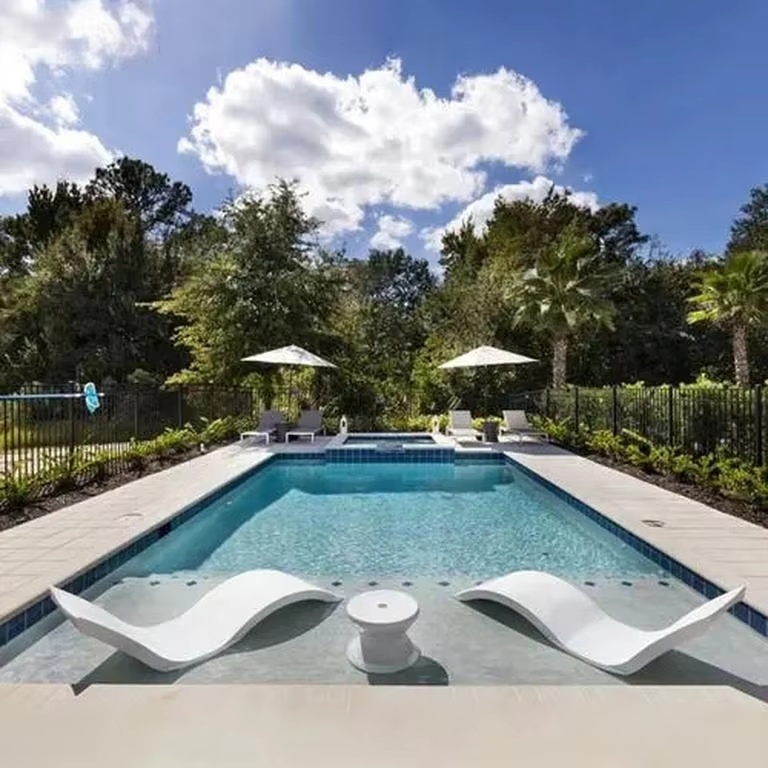 Swimming pool with a shallow Baja shelf and two white in-pool loungers
