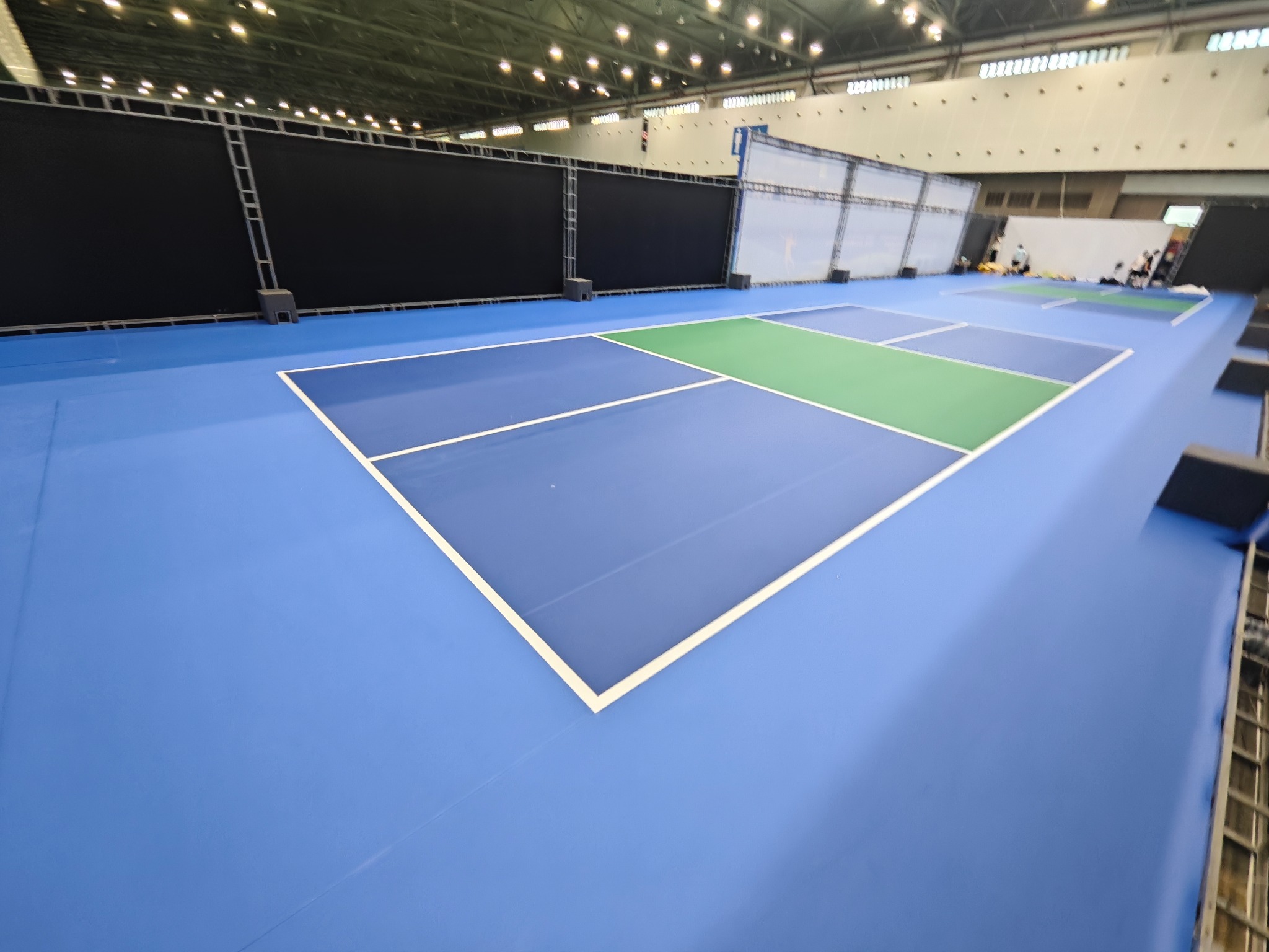 Temporary indoor blue and green pickleball courts in an event hall