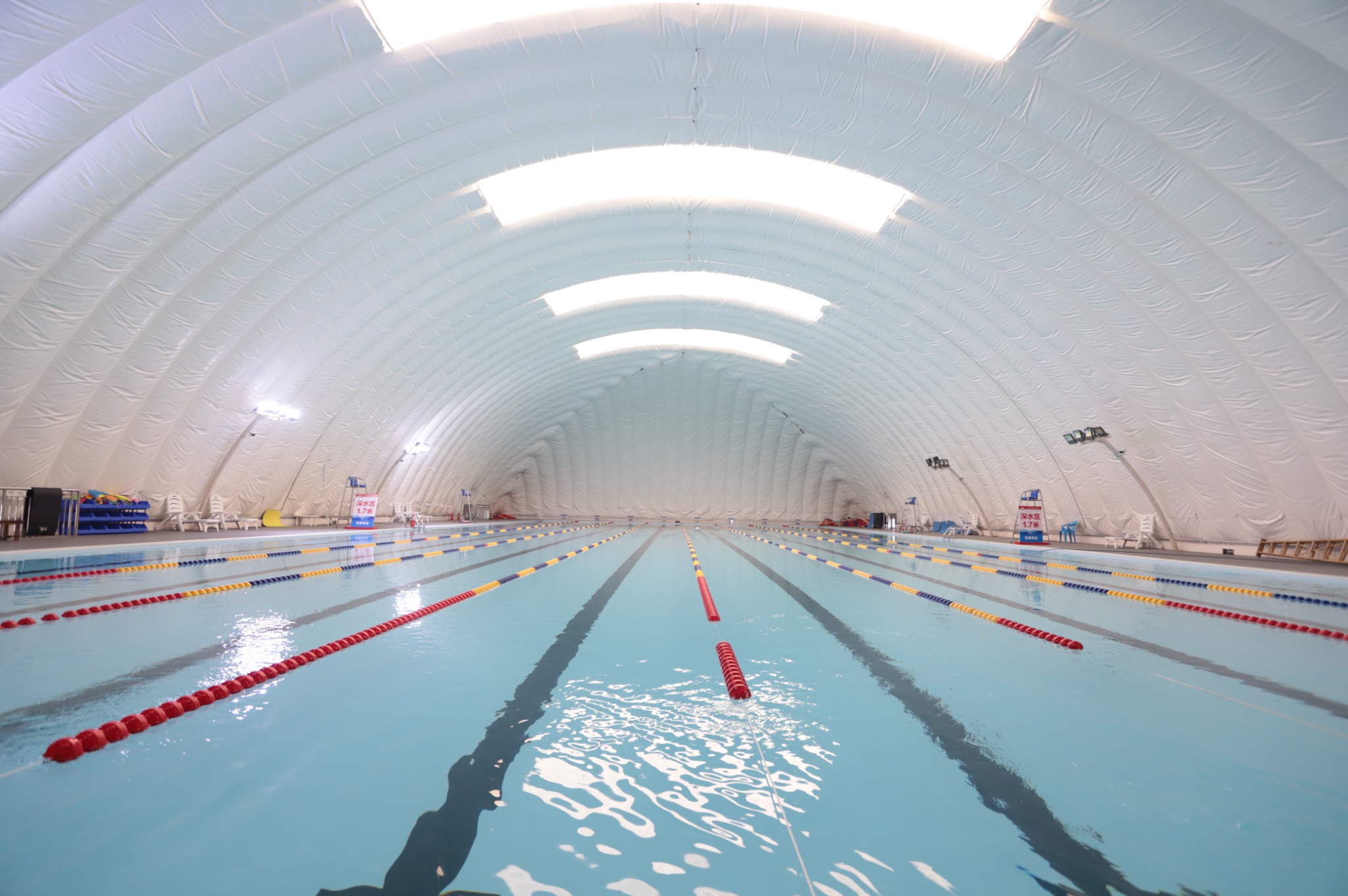 Long indoor swimming pool beneath a white air-supported dome