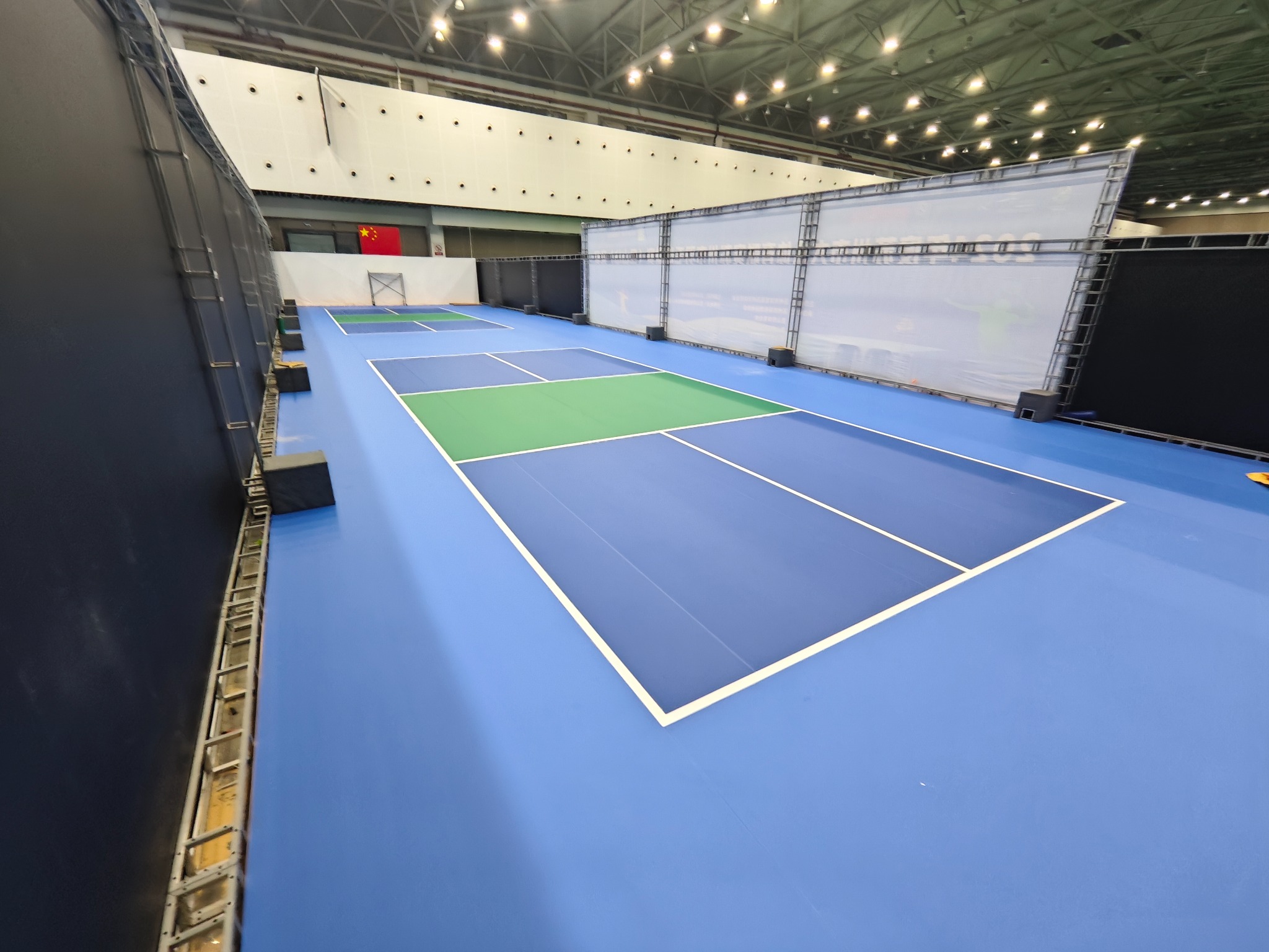 Indoor pickleball courts with blue surrounds and green playing zones