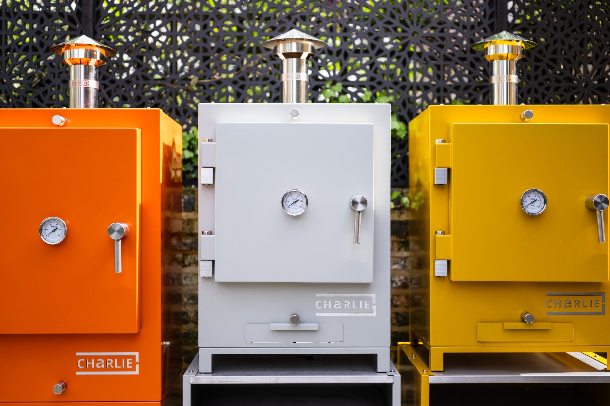 Three Charlie Ovens in different colours in a garden