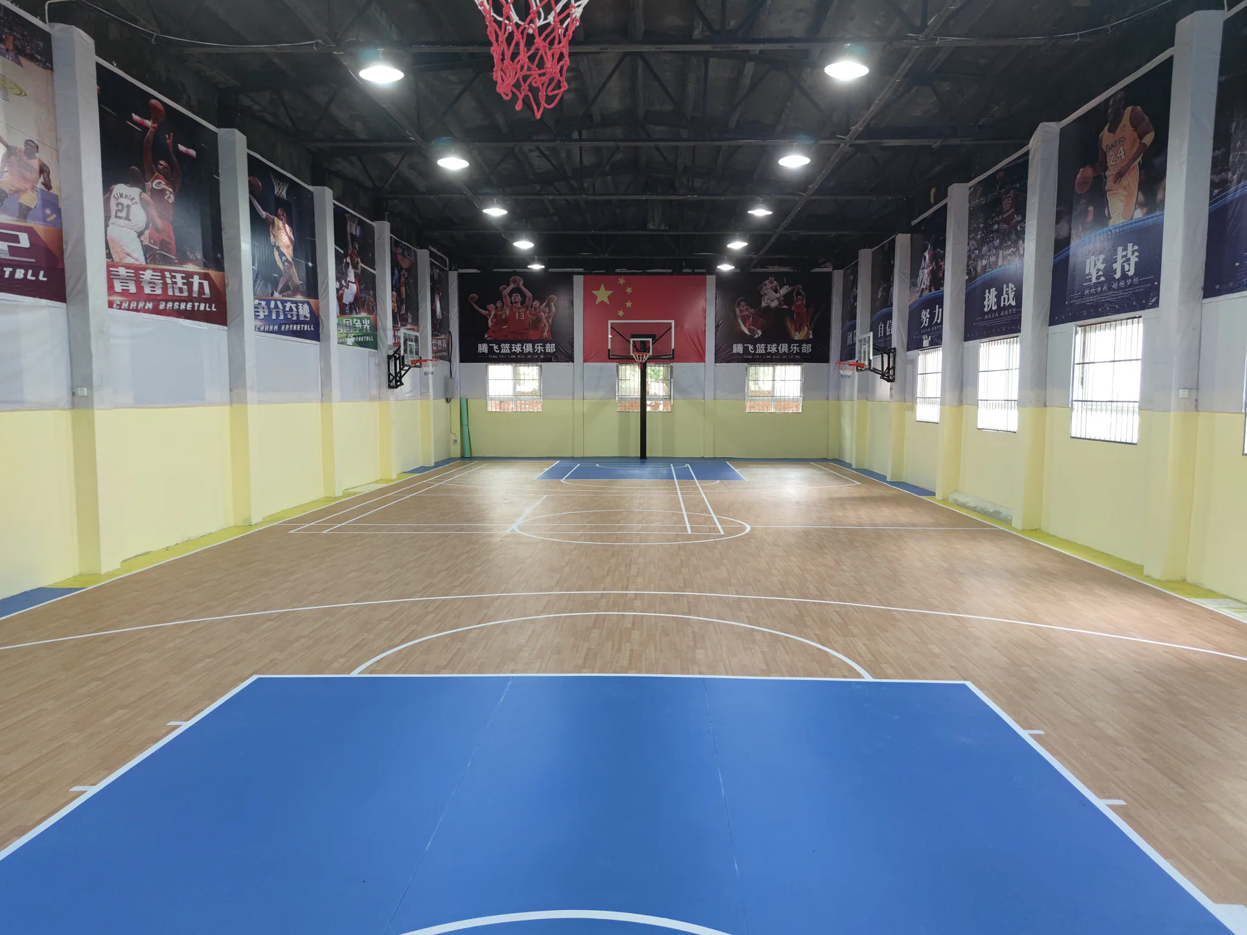 Large indoor basketball training hall with wood-pattern flooring