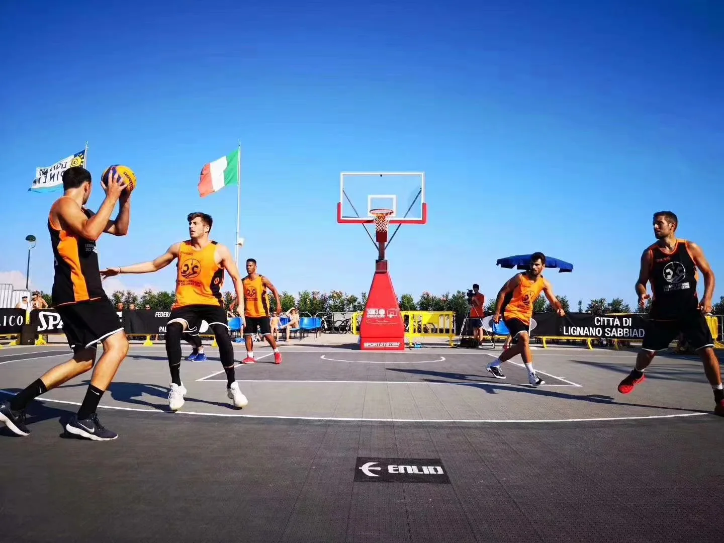 Players competing on an outdoor Enlio 3x3 basketball court