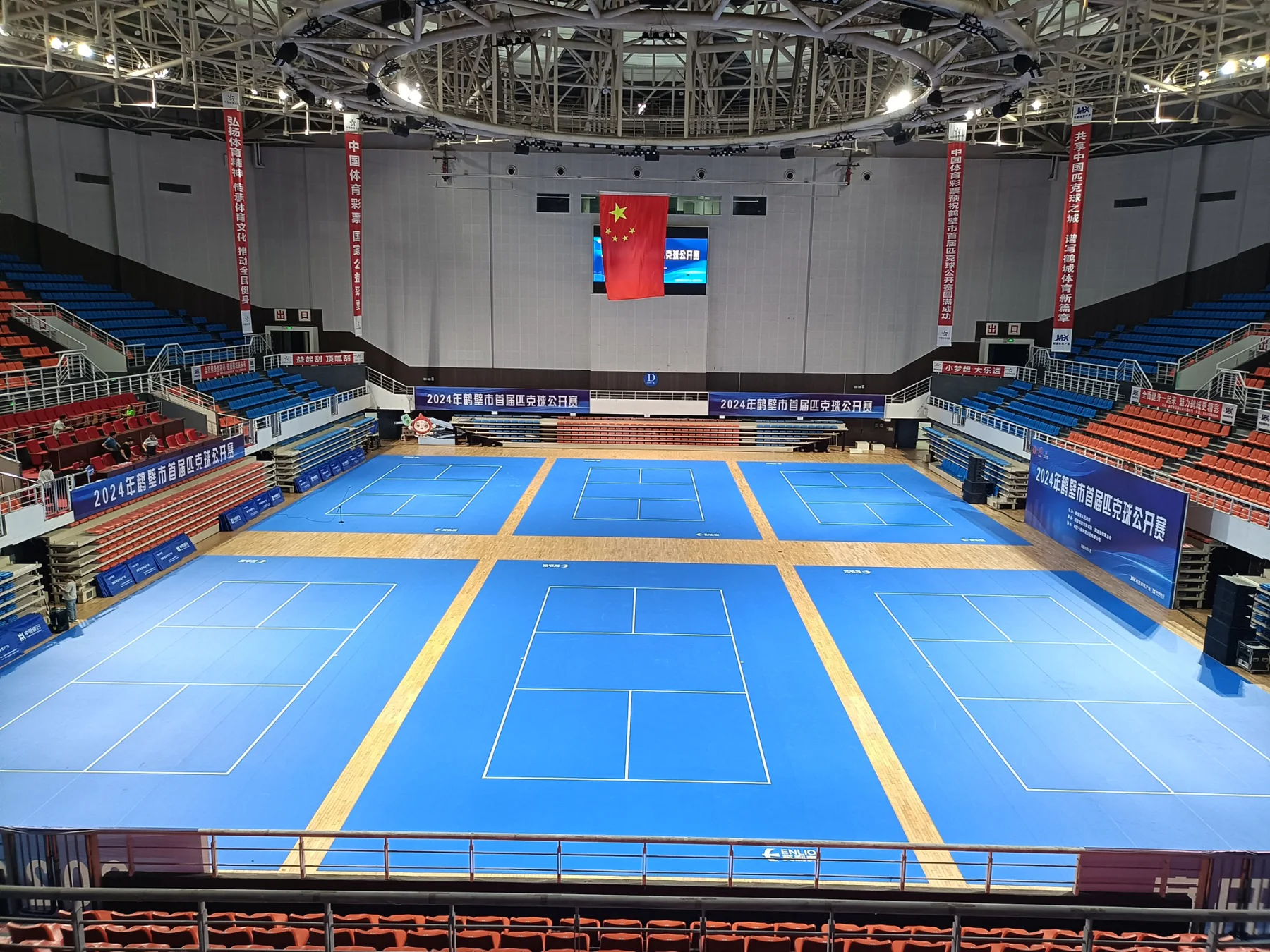 Indoor arena configured with six blue pickleball courts