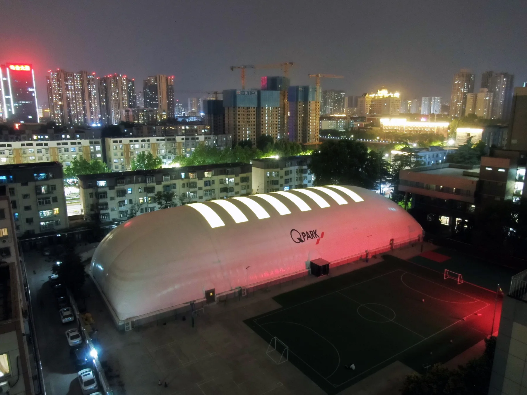 Illuminated air-supported sports dome in a city at night
