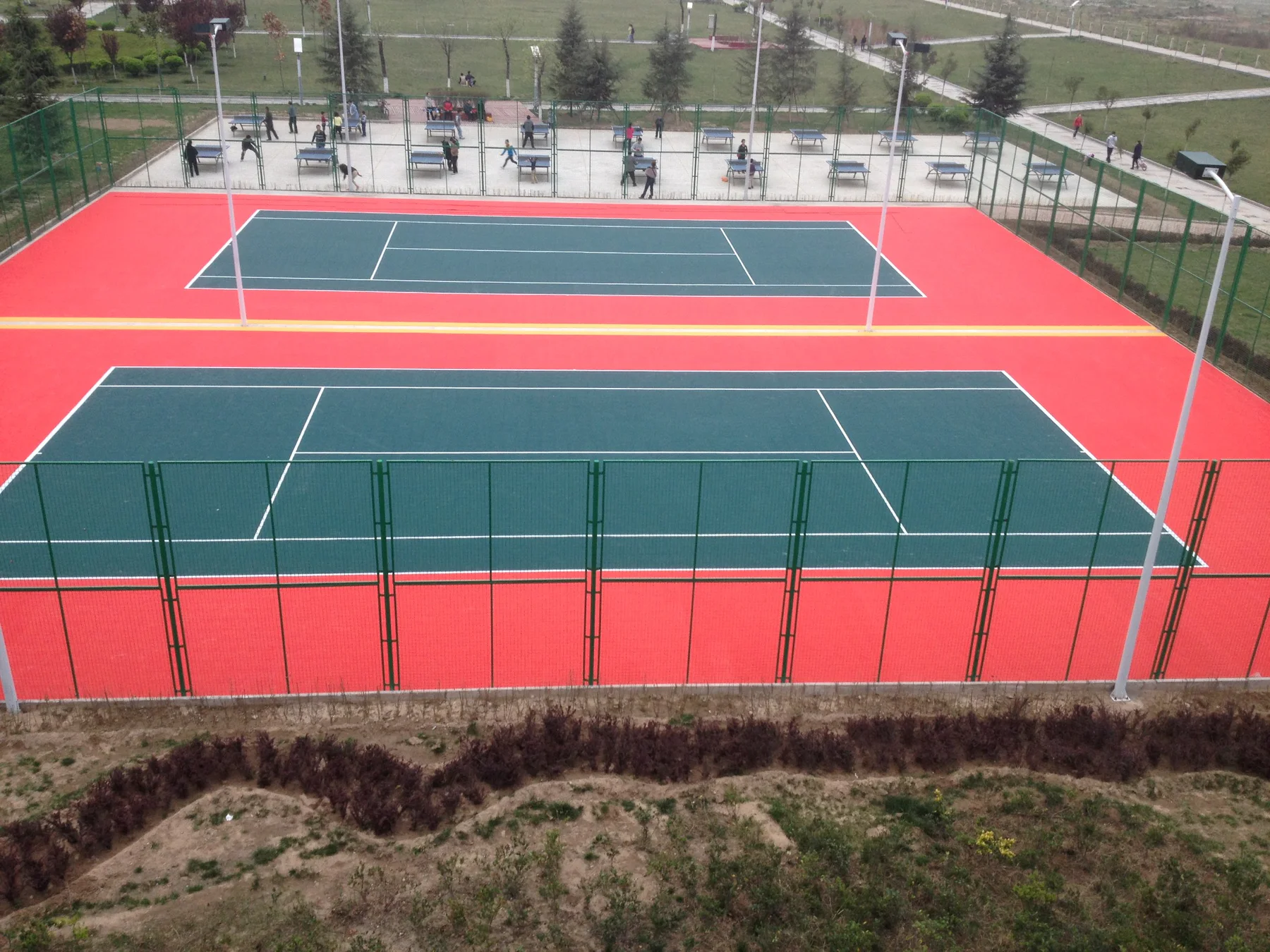 Red and dark green outdoor tennis courts in a public park