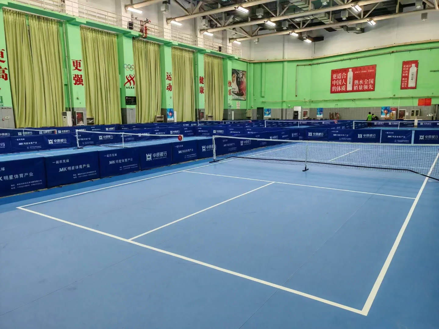 Indoor blue pickleball courts separated by barriers
