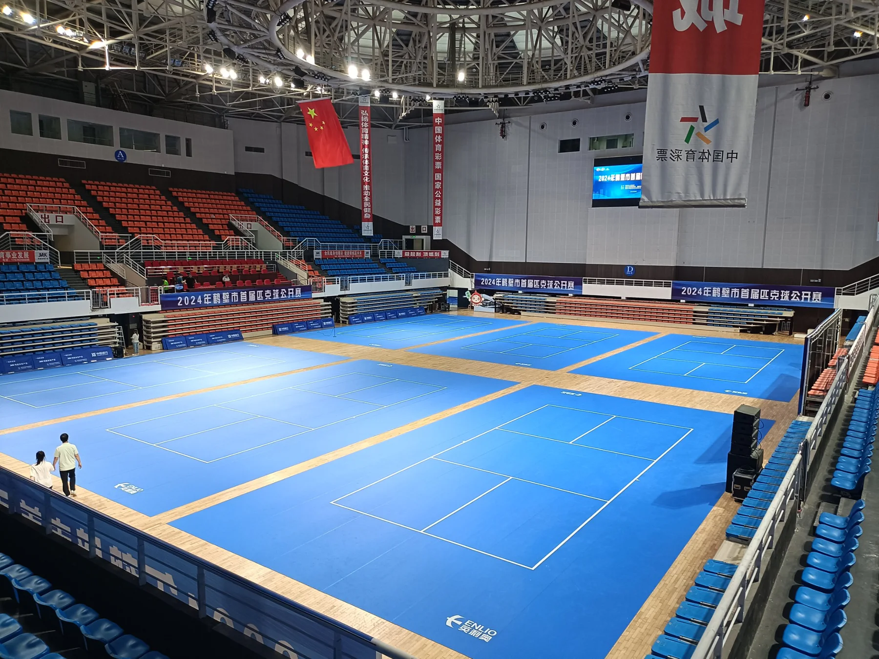 Indoor arena with multiple blue pickleball courts