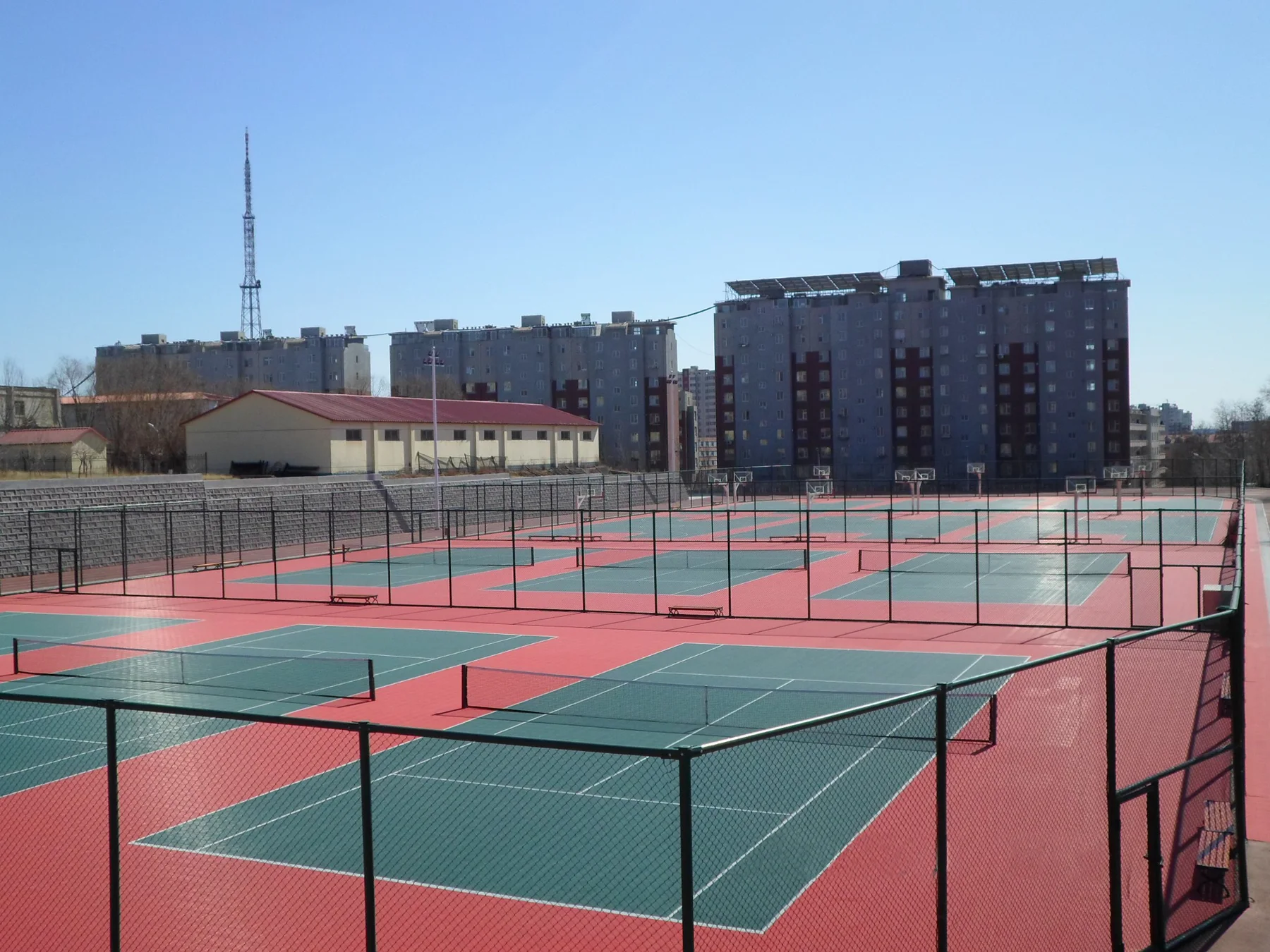 Large red and green fenced tennis-court complex