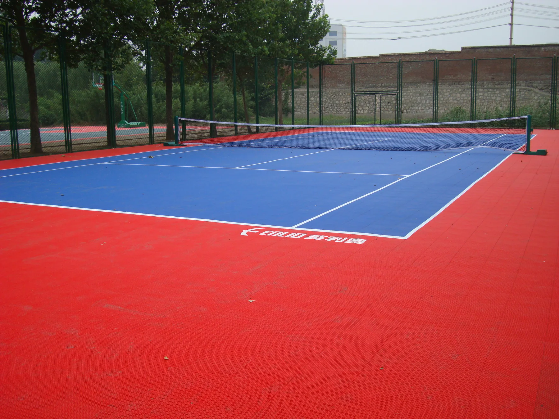 Red and blue Enlio outdoor tennis court viewed from court level