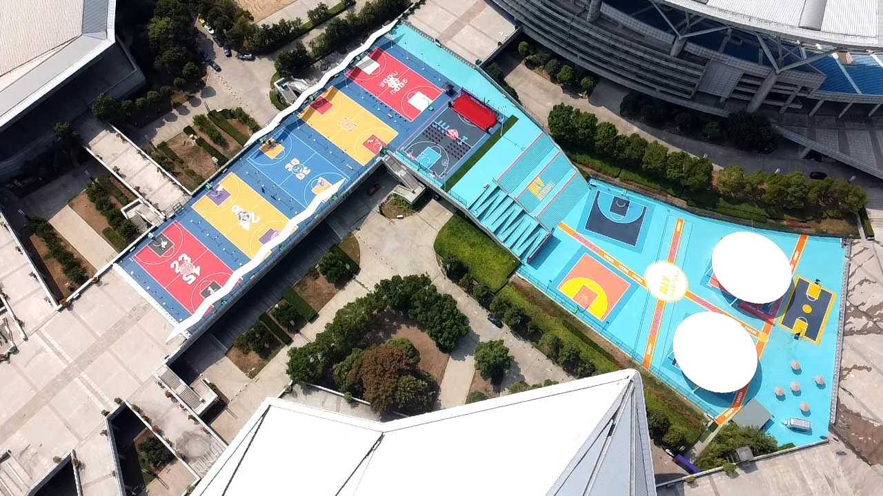 Daytime aerial view of a colourful multi-court basketball precinct